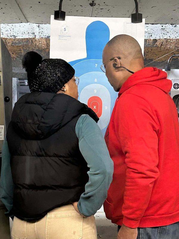 A Down Range instructor and a student reviewing her silhouette target together on the firing line.